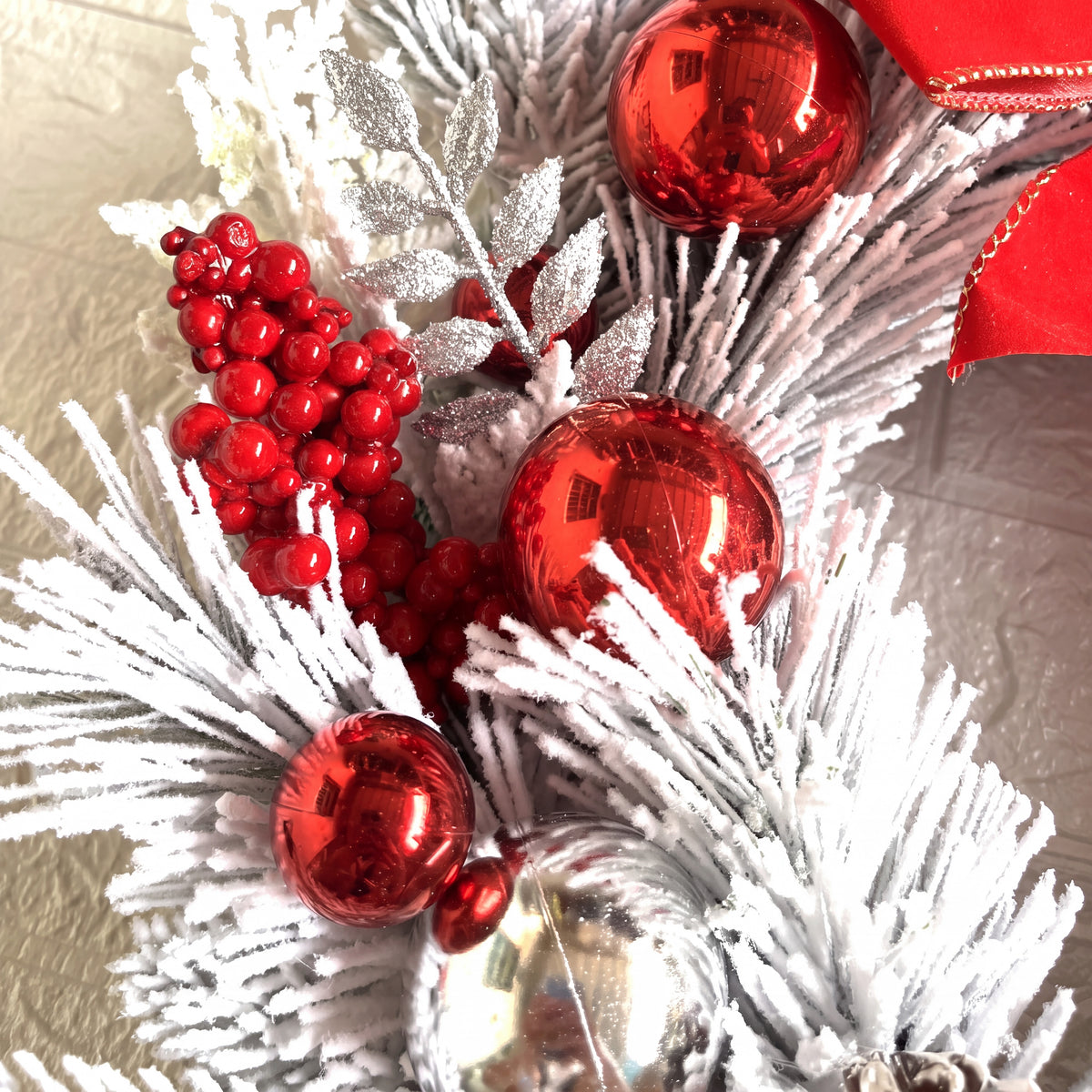 Detail van besneeuwde takken met rode kerstballen en bessen